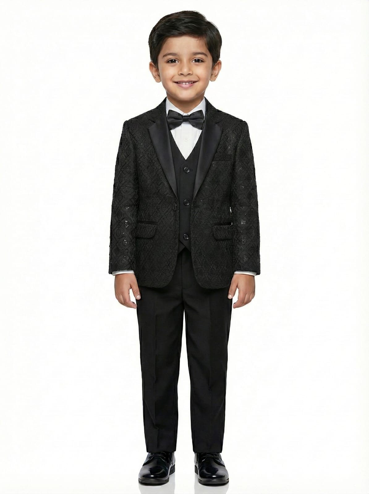 Young boy wearing a black tuxedo with a bow tie on a white background