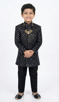 Child wearing a black embroidered sherwani on a white background