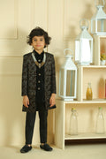 Person wearing a black lace dress standing in front of a shelf with decorative items.