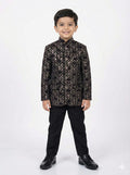 Young boy wearing a black and gold patterned suit on a white background