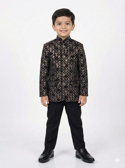 Young boy wearing a black and gold patterned suit on a white background