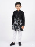 Young boy wearing a black embroidered traditional outfit on a white background