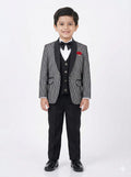 Young boy in a formal suit with a white shirt and black bow tie on a white background