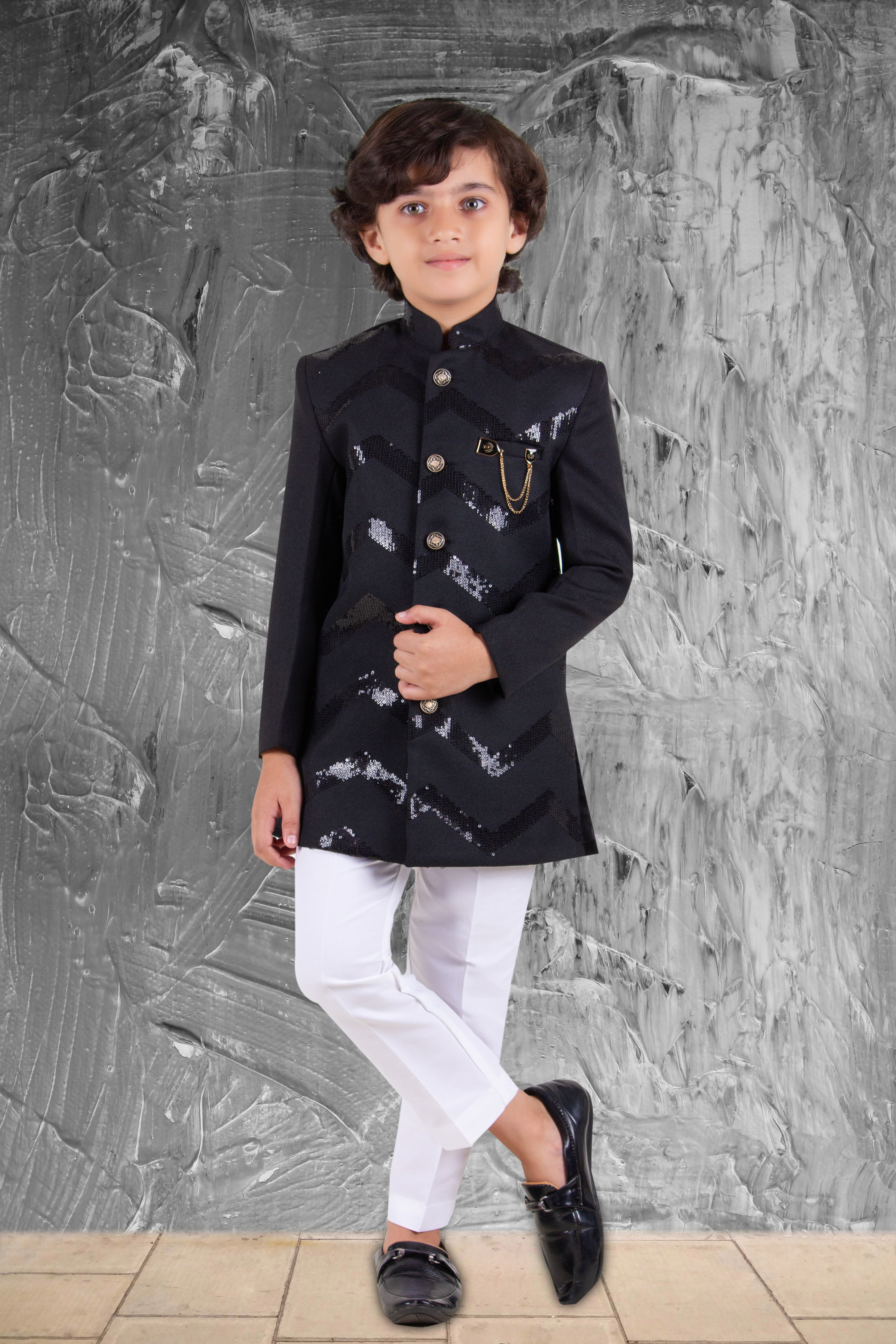 Child wearing a black and white outfit against a textured gray wall.