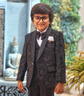 Child wearing a formal suit with a bow tie in an outdoor setting