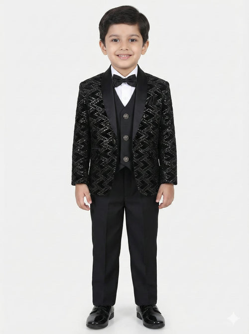 Young boy wearing a black patterned suit with a white shirt and bow tie on a white background
