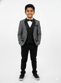 Young boy in a formal black and gray checkered suit with a bow tie on a white background