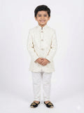 Young boy wearing a traditional white embroidered jacket and pants on a white background