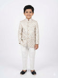 Young boy wearing a traditional cream-colored sherwani on a white background