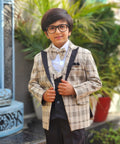 Child wearing a formal outfit with suspenders and bow tie in an outdoor setting.