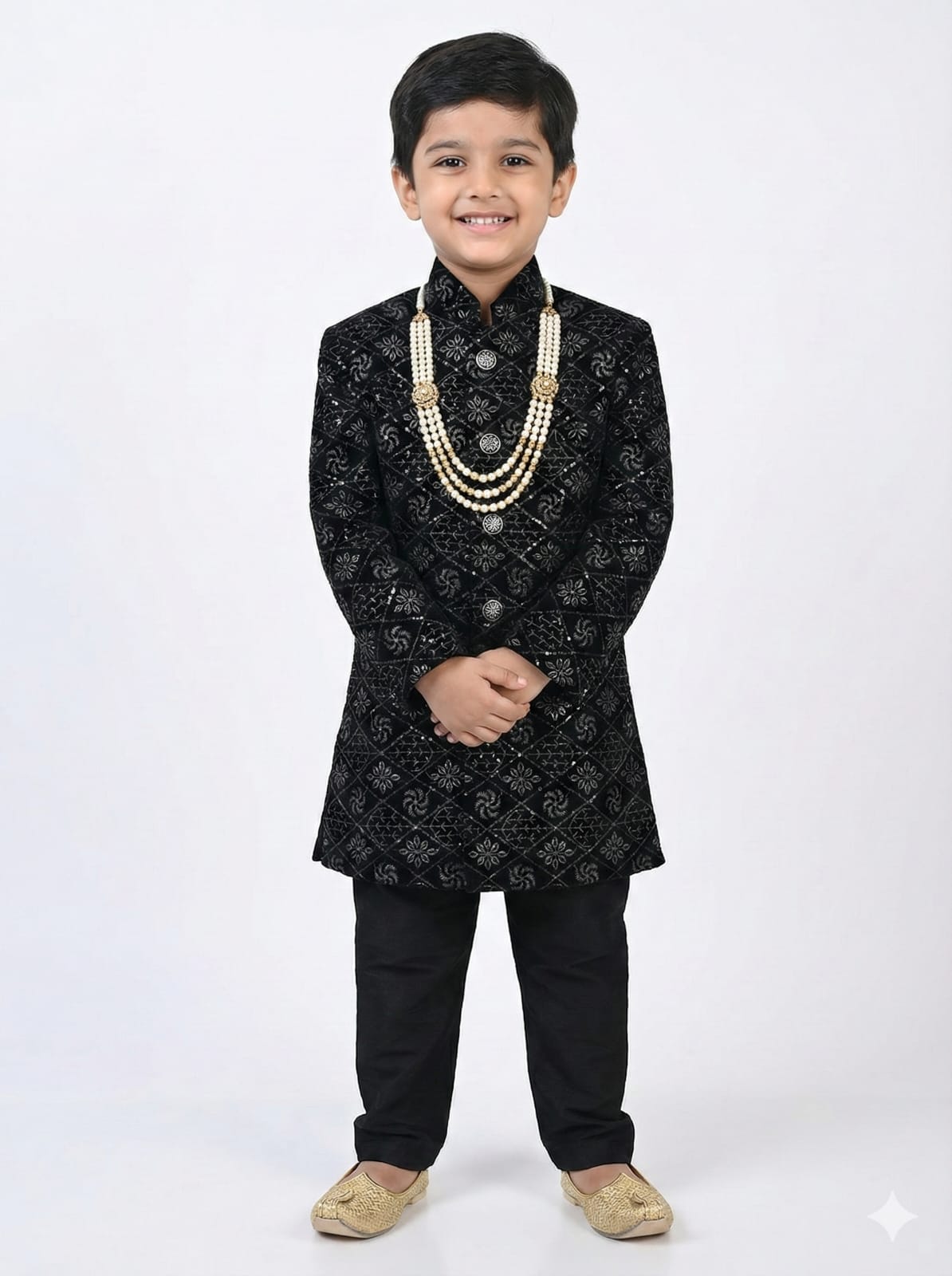 Young boy wearing a black traditional outfit with a white background