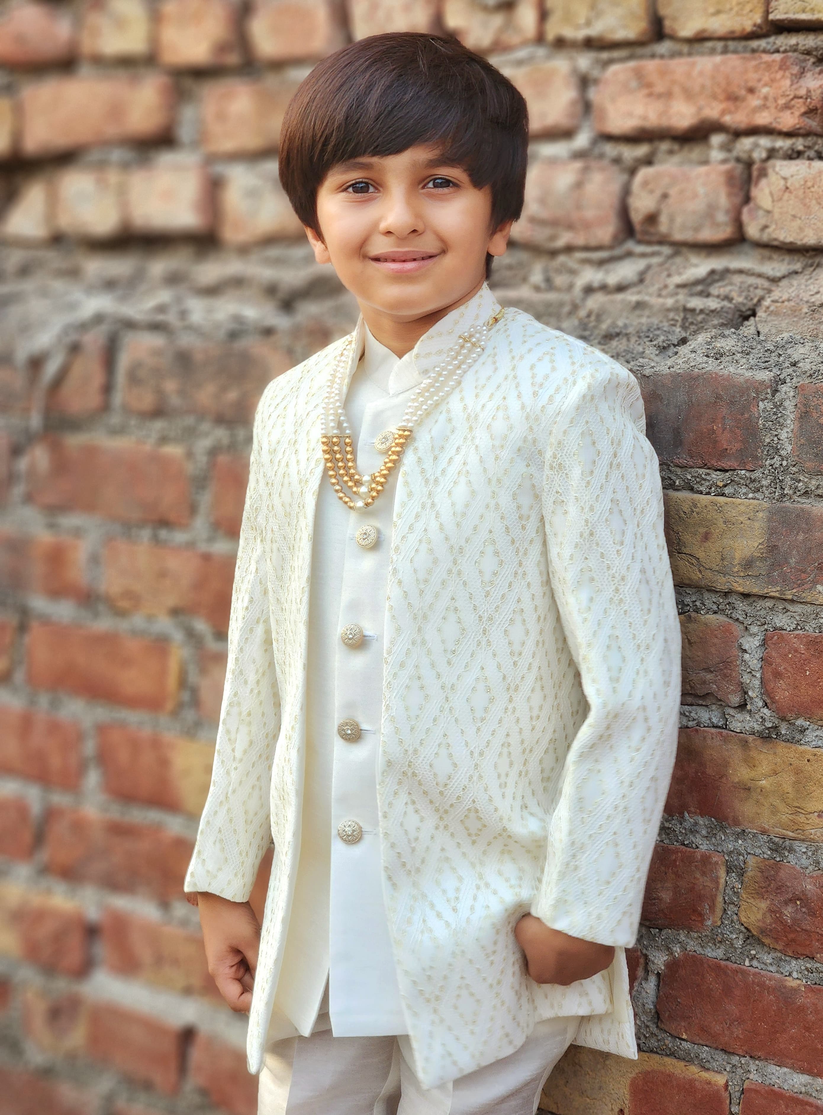 Young boy in formal attire standing against a brick wall