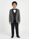 Young boy wearing a gray blazer, black vest, and pants on a white background