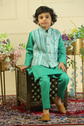 Person wearing a green outfit with a patterned shirt, standing on a decorative rug.