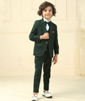 Child wearing a green suit with a white shirt and bow tie against a beige background