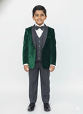 Young boy wearing a green velvet suit with a white shirt and black bow tie on a white background