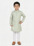 Young boy wearing a light green kurta with white pants on a white background