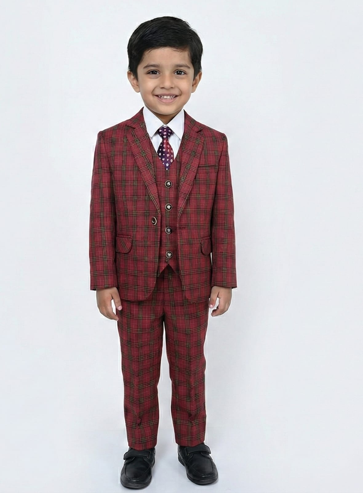 Young boy wearing a red plaid suit with a white shirt and patterned tie on a white background