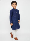 Young boy wearing a navy blue kurta with white pants on a light gray background