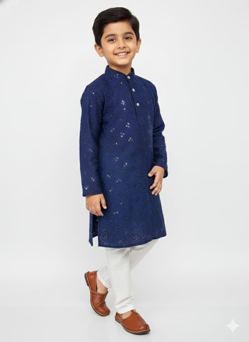 Young boy wearing a navy blue kurta with white pants on a light gray background
