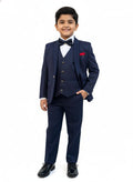 Young boy wearing a navy blue suit with a white shirt and black shoes on a white background
