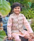 Child wearing a traditional outfit with a patterned vest and pink shirt, sitting outdoors.