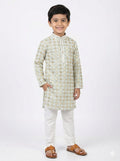 Young boy wearing a traditional kurta with white pants on a white background