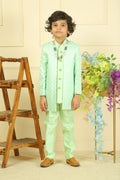 Person wearing a light green outfit with floral patterns, standing next to a wooden chair and floral decorations.