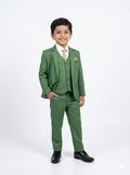Young boy wearing a green suit with a white shirt and black shoes on a white background