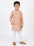 Young boy wearing a floral kurta with white pants on a white background