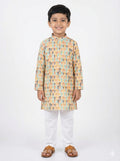 Young boy wearing a patterned kurta with white pants on a white background