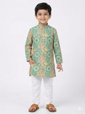 Child wearing a green patterned kurta with white pants on a white background