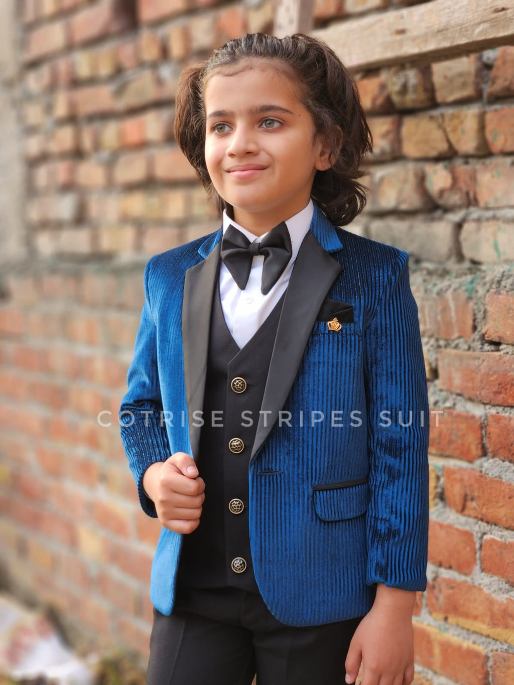Child wearing a blue striped suit with a brick wall background
