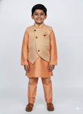 Young boy wearing a traditional peach kurta with jacket on a white background