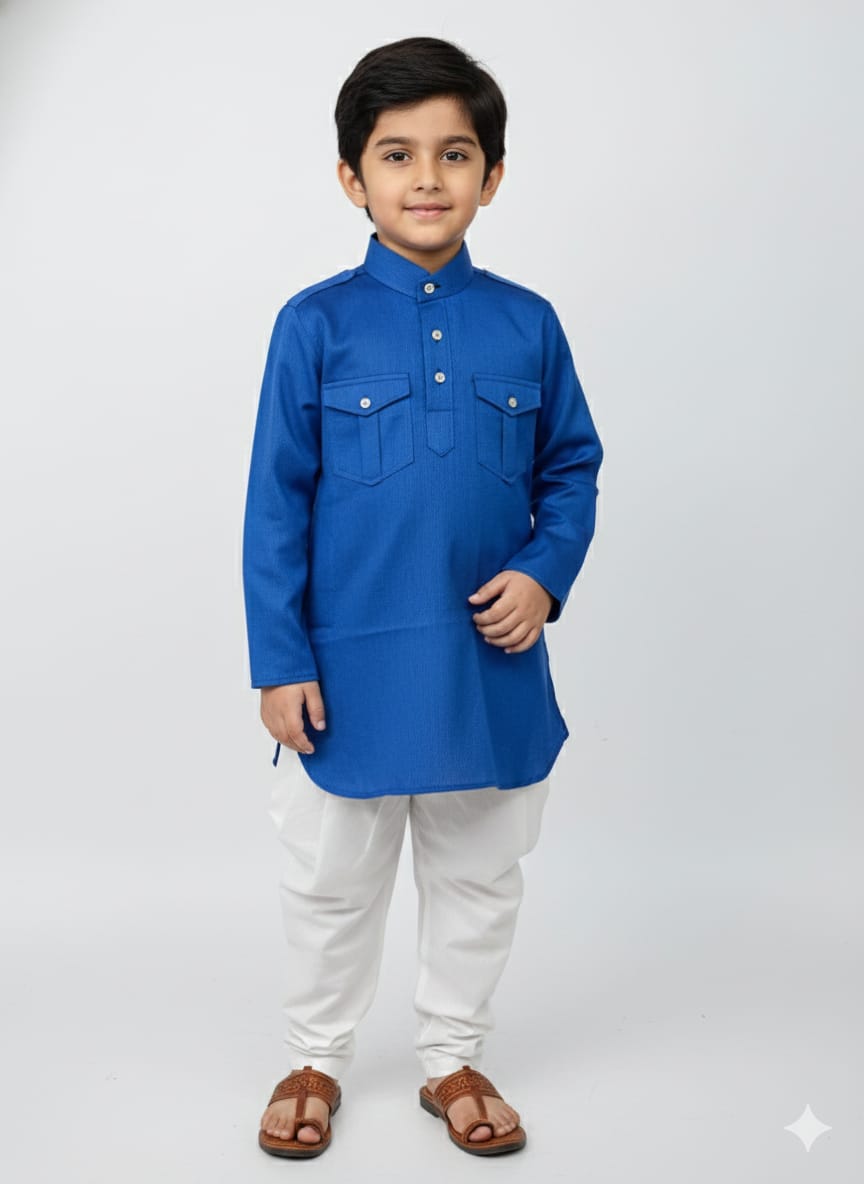 Young boy wearing a blue kurta with white pants on a light gray background