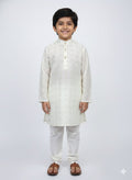 Young boy wearing a white kurta with white pants on a white background
