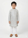 Young boy wearing a traditional kurta with white pants on a light gray background