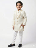 Young boy wearing a traditional white sherwani on a white background