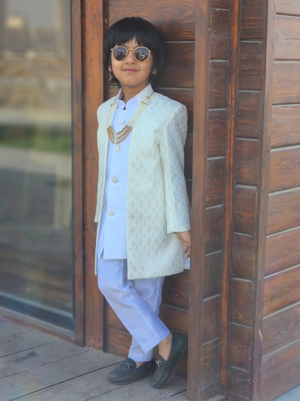 Child in formal attire standing in a wooden doorway