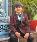 Child in formal attire sitting outdoors with a statue and plant in the background